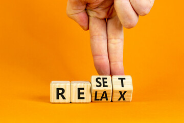 Relax and reset symbol. Businessman turns cubes and changes the word 'relax' to 'reset'. Beautiful orange table, orange background. Business, relax and reset concept. Copy space.
