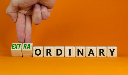 Ordinary or extraordinary symbol. Businessman turnes wooden cubes and changes words 'Ordinary...