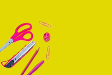 scattered office equipment on a yellow background. pink stationery