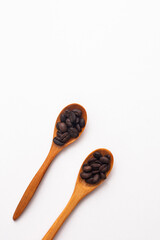 coffee beans in a short wooden spoon and a long wooden spoon