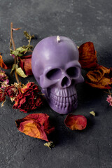Candle skull with rose petals on a black background.