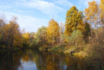 Autumn lake. Forest, fishermen fishing on the autumn lake. The lake is surrounded by trees with yellow foliage. Late autumn. Autumn landscape. Russia.