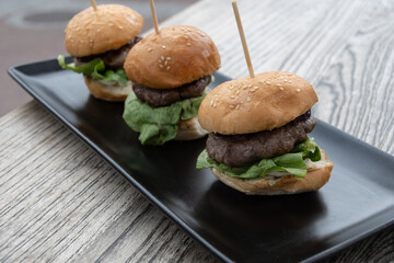 three delicious mini burger on a black plate