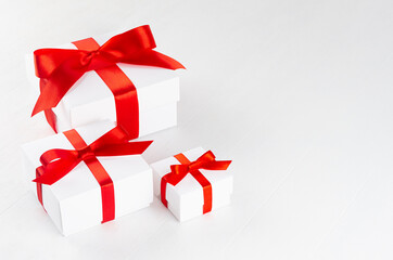 Elegant white present boxes different size with red ribbon on wood table, top view, copy space.