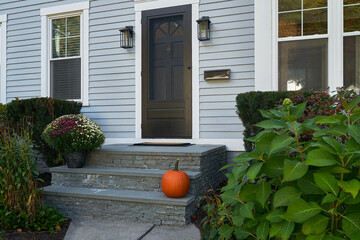 Chrysanthemums and a pumpkin on the front doorsteps of a home in autumn