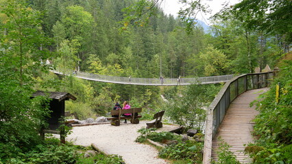junge Wanderer beobachten weitere Wanderer auf der Hängebrücke im Klausbachtal im Nationalpark...