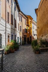 An alley leading through the traditional homes in the Trastevere neighborhood of Rome on a bright sunny day.