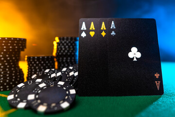 Stylish black cards and stacks of black chips on a green gambling table cloth. Multicolored smoke background. Casino. Online casino. Gambling, poker, gambling, risk, chance for luck.