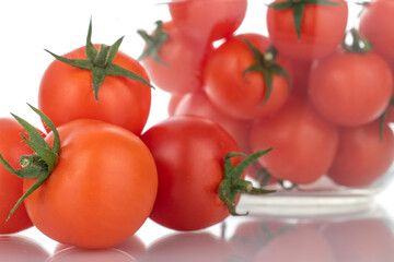 Several red organic tomatoes with glassware, close-up, isolated on white.