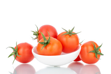 Several red organic tomatoes with a white ceramic saucer, close-up, isolated on white.