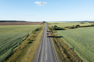 Straight asphalt road among green agriculture fields in Russia