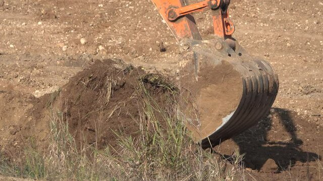 Excavator bucket digs the ground
