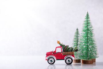 Christmas Car carrying fir tree over silver background with New Year spruce trees on snow
