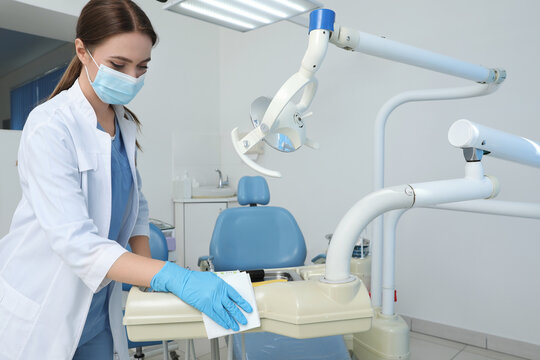 Professional Dentist In White Coat And Medical Mask Cleaning Workplace Indoors