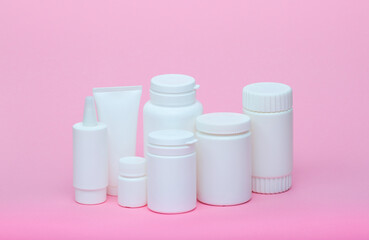 White different medecine or cosmetic jars on a pink background as a concept of cosmetology of medecine and treatment
