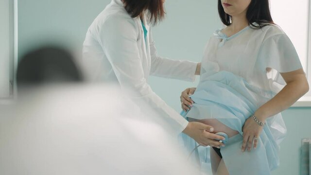 Competent obstetrician-gynecologist checking baby heart beating of pregnant woman at hospital ward. Young woman in expectation getting medical support before labour.