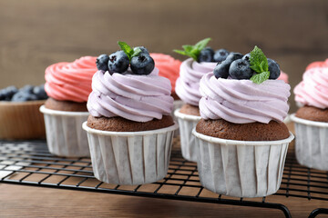 Sweet cupcakes with fresh blueberries on wooden table, closeup