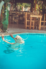 a Rastafarian girl swims in the hotel pool