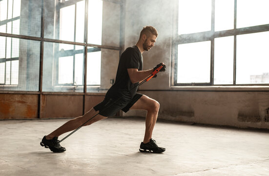 Fit sportsman exercising with resistance band in gym