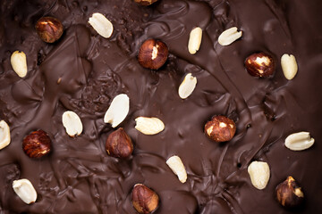chocolate background with peanuts and hazelnuts close-up, top view