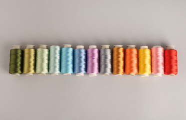 Different colorful sewing threads on light grey background, flat lay