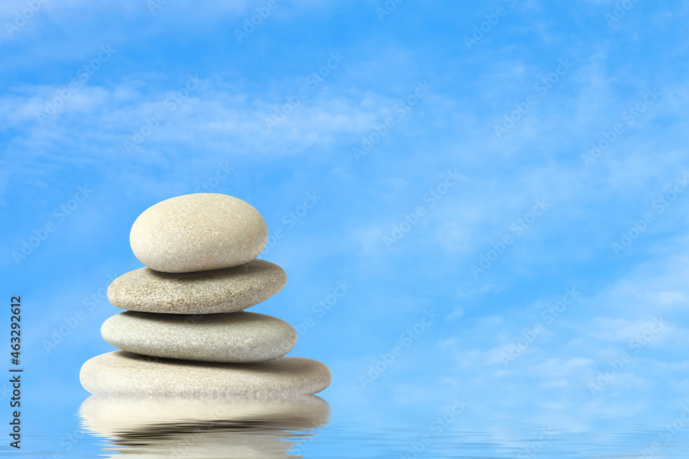 Poster sea stones in a stack in the water against the background of the sky with white clouds