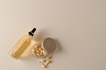 Rejuvenating cream serum in capsules and hyaluronic serum in a bottle on a beige background