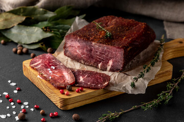still life composition with a piece of red smoked dry ham on a wooden cutting board, side view