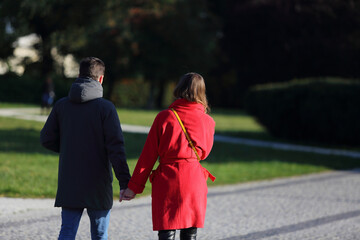 	
Para młodych ludzie, kobieta i mężczyzna spaceruje deptakiem, chodnikiem w parku.	

