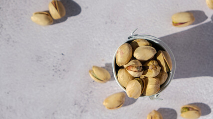Pistachios in white bucket on concrete background. Healthy and dietary nutrition. Concept of nuts....