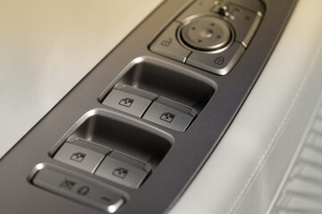 Close up view of button controlling window in modern car interior. Vehicle interior detail. Door handle with windows controls