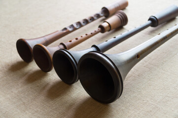 Four musical woodwind folk instruments - zhaleika and three schalmeis - lie diagonally on a gray...