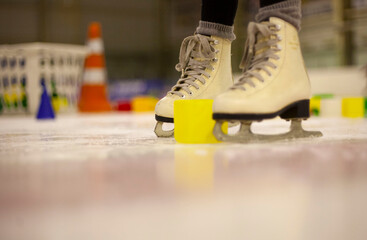 Little girl learns to skate. Children's skates. A child training on ice. The concept of children's...