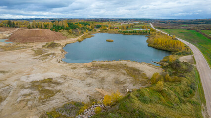 Open pit gravel mining. Little lake or pond of unusual shape with a beautiful autumn nature and...