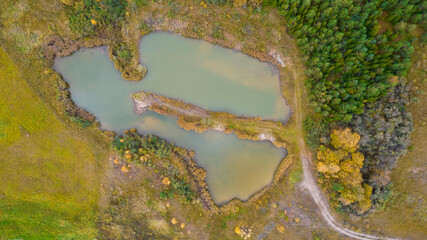 Little lake or pond of unusual shape with a beautiful autumn nature photographed from above with a drone. Real is beautiful 