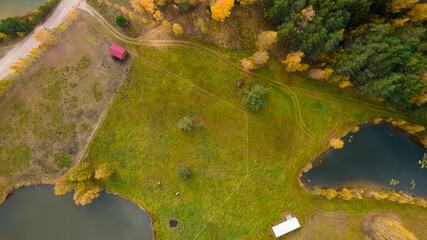 Little lake or pond of unusual shape with a beautiful autumn nature, small house and gravel road photographed from above with a drone. Real is beautiful 