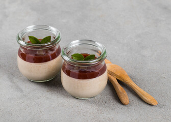 Creamy fruit jelly, Plum Panna Cotta with topping in a glass on a light gray background