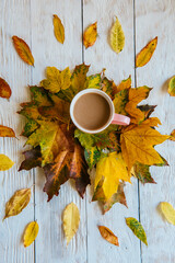 Coffee cup and yellow autumn leaves background. Still life, top of view, flat lay.