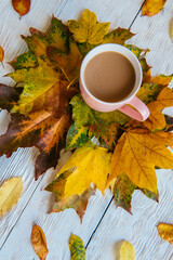 Coffee cup and yellow autumn leaves background. Still life, top of view, flat lay.