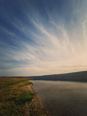 Fototapeta na wymiar Scenic view to the riverbank of Nistru river, Moldova. Vertical background, calm water flowing. Natural landscape, silent empty place