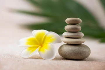 Foto op Canvas Pyramids of gray and white zen pebble meditation stones on beige background with plumeria tropical flower. Concept of harmony, balance and meditation, spa, massage, relax © strigana