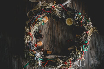 Creative Christmas wreath with sweets. An unusual idea for a holiday home decor. Natural interior decor on wooden background.