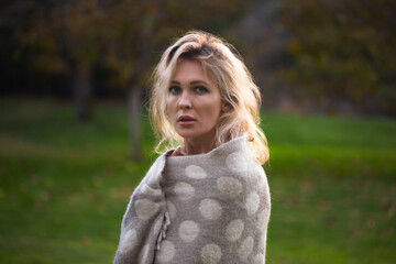 beautiful one woman in park emotional  in gray plaid or blanket  with white dots