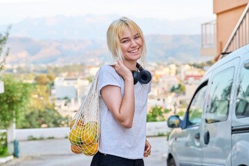 Portrait of a female teenager with oranges in an eco-friendly mesh bag