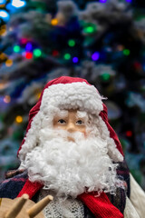 Christmas decor skiing santa in cable knit sweater in front of bokeh flocked Christmas tree - selective focus