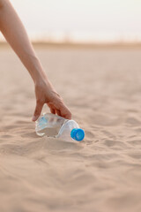 a man collects plastic bottles and garbage on the beach in a public place. eco friendly and caring for nature. collect plastic muslr and take it for recycling. careful attitude to the planet