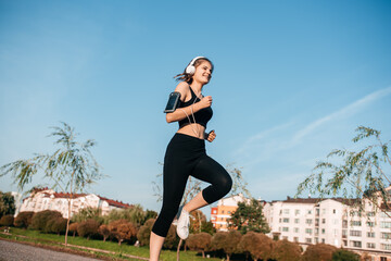 A girl in headphones is engaged in outdoor fitness in a metropolis. running and sports in summer