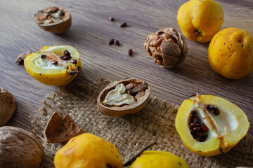 Quince fruits and walnut on wooden table. Autumn harvest concept. Autumn rustic still life. Wild quince apples with seeds and nuts. Ripe organic food. Seasonal dessert.