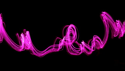 Long exposure photograph of neon pink colour in an abstract swirl, parallel lines pattern against a black background. Light painting photography.