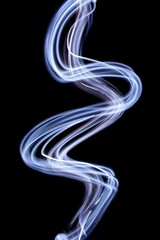 Fototapeta premium Long exposure photograph of bright white light in an abstract swirl, smokey waves pattern against a black background. Light painting photography.